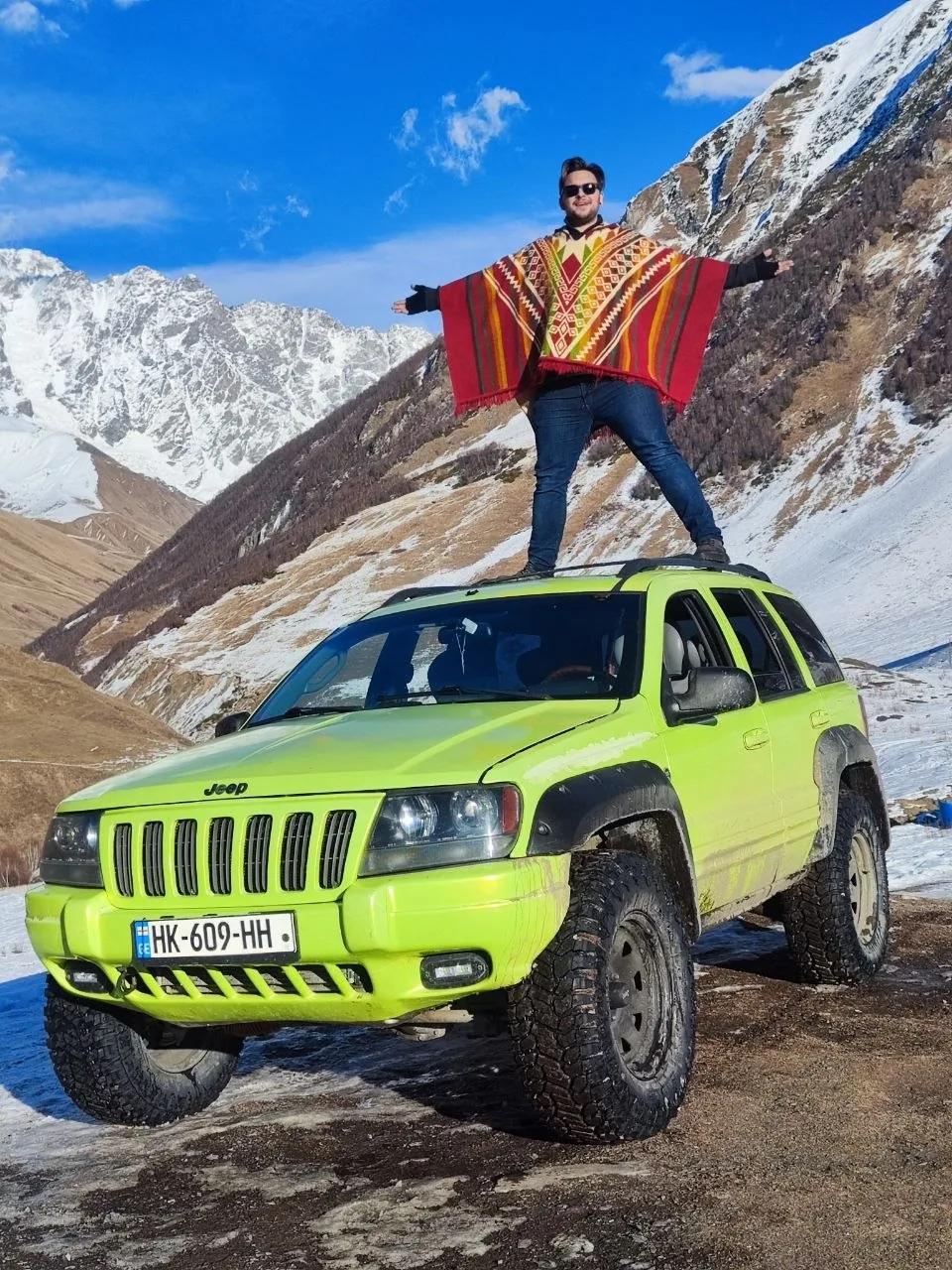 Philipp Gross Kochnov on the roof of his lifted Jeep Grand Cherokee WJ, snowy Caucasus